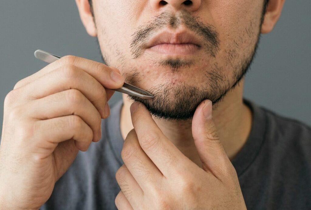 あごひげを毛抜きする男性