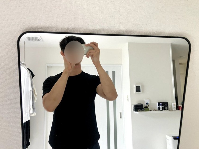 全身鏡で髪型と上半身のバランスをチェックしている様子