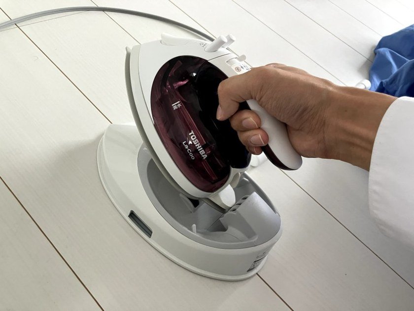 コードレスアイロンを給電台に戻す様子