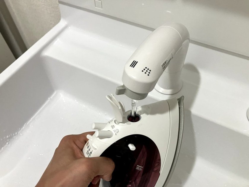 コードレスアイロンのカセットタンクに洗面台で給水している様子